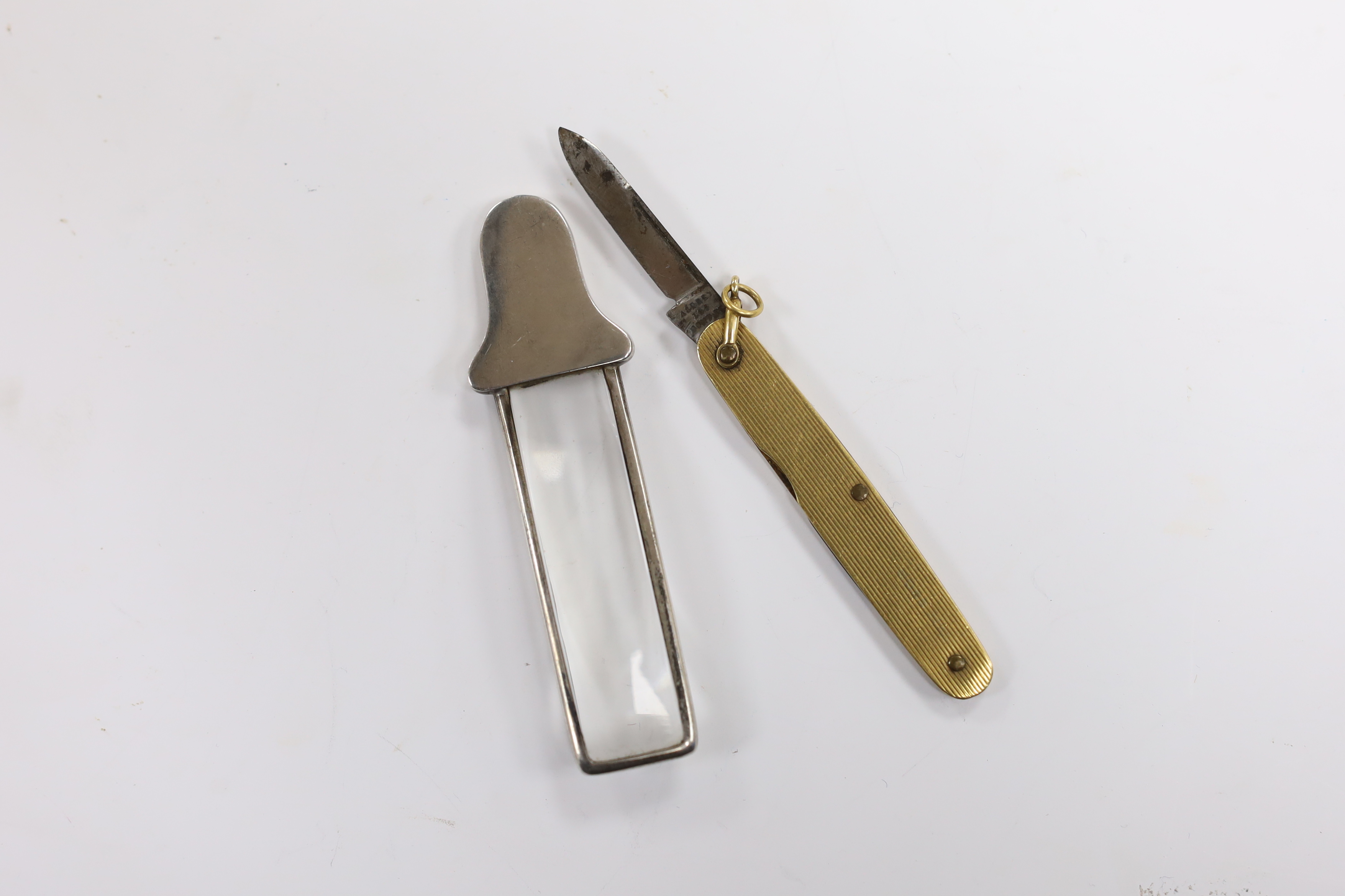 A small George V silver handled magnifying glass, by Asprey & Co Ltd, Birmingham, 1913, 85, together with a reeded yellow metal mounted penknife, retailed by Asprey.